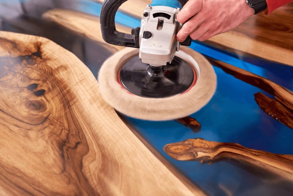 A worker polishing the wood to make custom epoxy tables - custom table build by Fox in the Sawdust